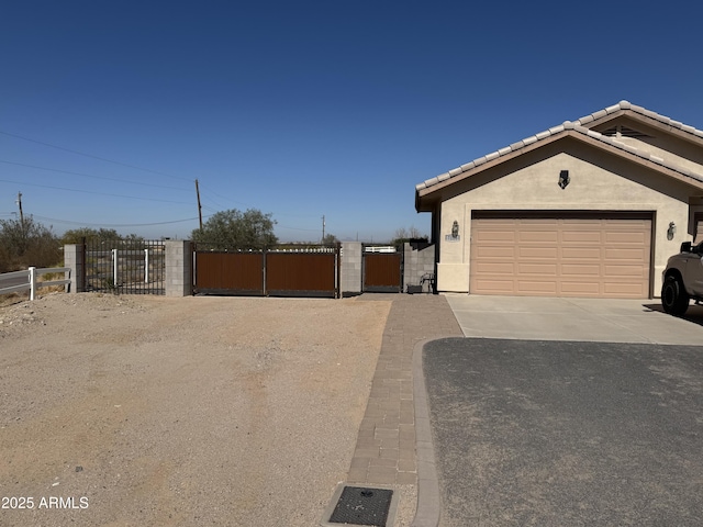 ranch-style house with stucco siding, a gate, fence, driveway, and a tiled roof