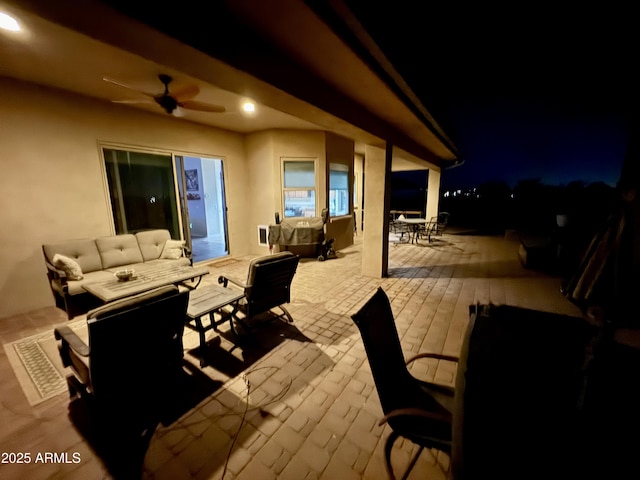 patio at night featuring outdoor dining area, ceiling fan, and outdoor lounge area