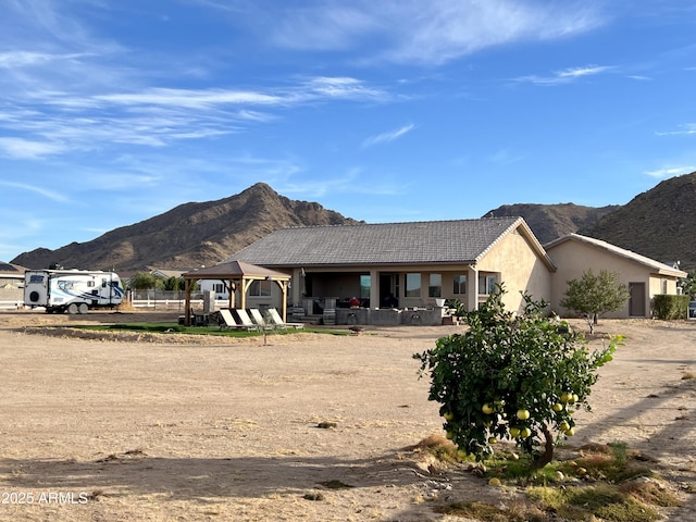 ranch-style house with a gazebo, a mountain view, and stucco siding