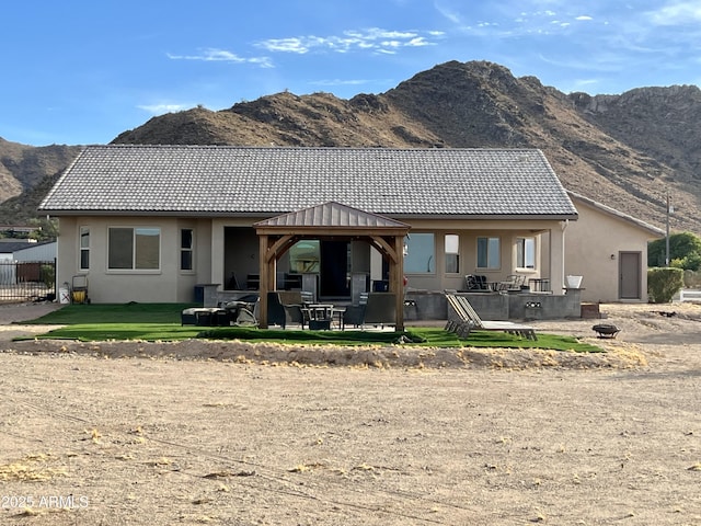 back of house with stucco siding, a tiled roof, a mountain view, and a gazebo