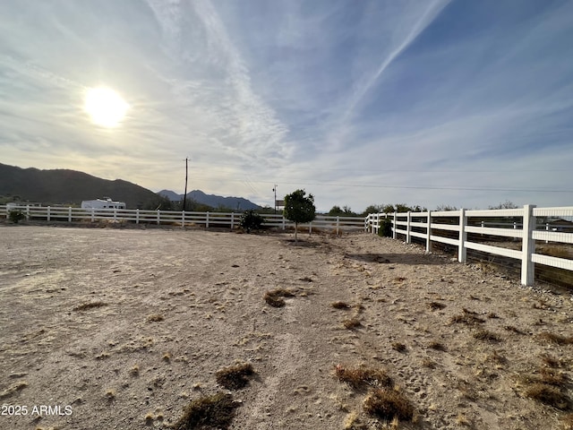 view of yard featuring a rural view, fence, and a mountain view