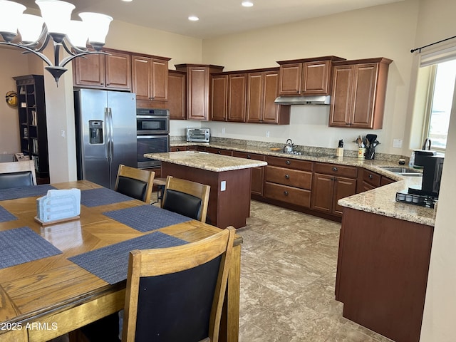 kitchen with stainless steel fridge, a kitchen island, light stone counters, double wall oven, and black electric stovetop