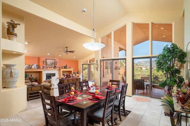 dining room with ceiling fan, vaulted ceiling, a fireplace, and light tile patterned floors