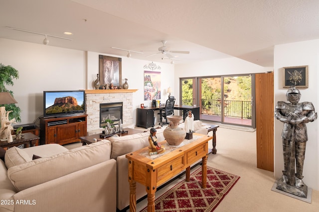 carpeted living area with rail lighting, ceiling fan, and a fireplace