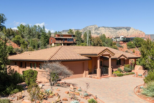 view of front of property with decorative driveway, a tile roof, stucco siding, a mountain view, and a garage