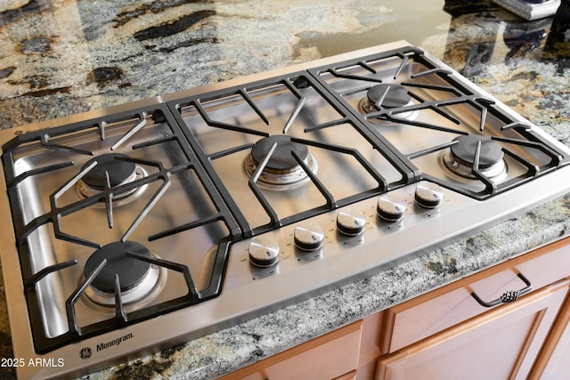 details with light stone countertops and stainless steel gas stovetop