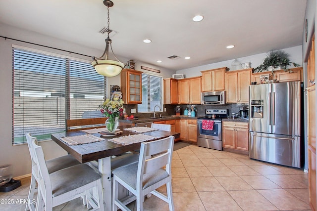 kitchen featuring sink, hanging light fixtures, light tile patterned floors, stainless steel appliances, and decorative backsplash