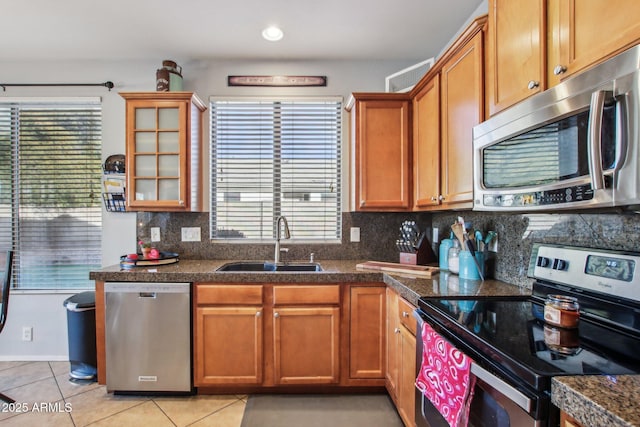 kitchen featuring sink, decorative backsplash, light tile patterned floors, and appliances with stainless steel finishes