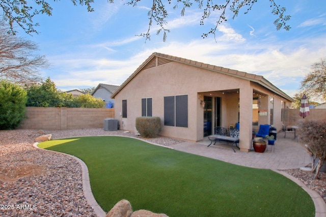 rear view of house with central AC unit, a lawn, and a patio