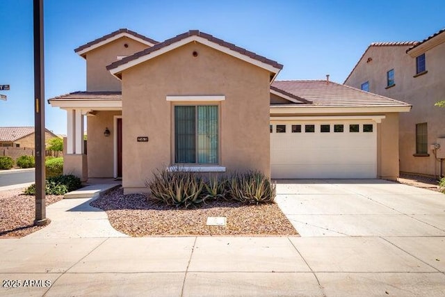 mediterranean / spanish-style home featuring a garage, concrete driveway, a tiled roof, and stucco siding