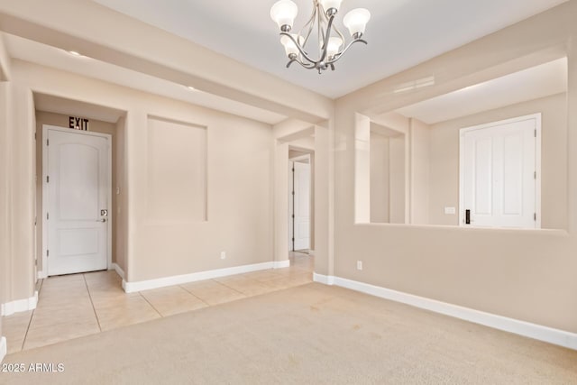 carpeted spare room featuring baseboards, tile patterned flooring, and a notable chandelier