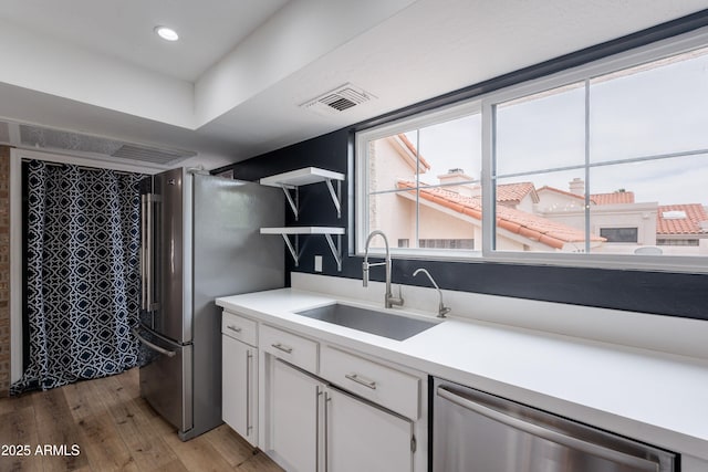 7800 E Lincoln Dr Unit 2029, Scottsdale, AZ 85250 - kitchen with appliances with stainless steel finishes, a sink, open shelves, light wood finished floors, and white cabinets