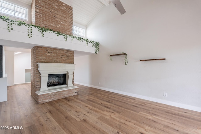 7800 E Lincoln Dr Unit 2029, Scottsdale, AZ 85250 - unfurnished living room featuring high vaulted ceiling, hardwood / wood-style flooring, baseboards, a fireplace, and beam ceiling