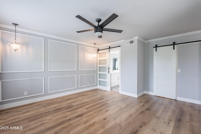 7800 E Lincoln Dr Unit 2029, Scottsdale, AZ 85250 - unfurnished bedroom with a barn door, ornamental molding, wood finished floors, baseboards, and ensuite bath