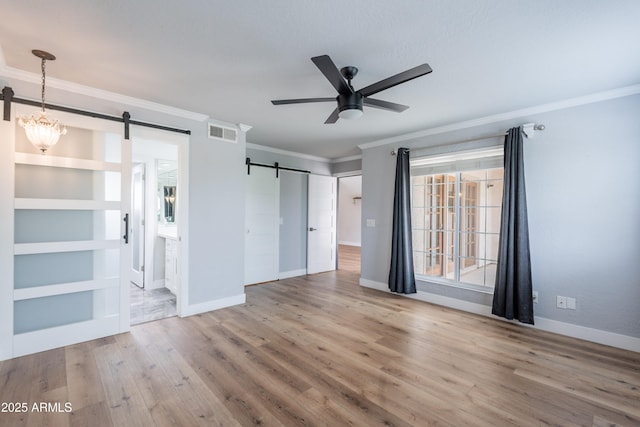 7800 E Lincoln Dr Unit 2029, Scottsdale, AZ 85250 - unfurnished bedroom featuring a barn door, ornamental molding, baseboards, wood finished floors, and connected bathroom