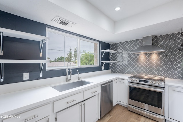 7800 E Lincoln Dr Unit 2029, Scottsdale, AZ 85250 - kitchen with stainless steel appliances, wall chimney range hood, a sink, white cabinetry, and light wood-type flooring