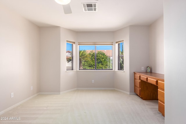 carpeted bedroom with built in desk and ceiling fan