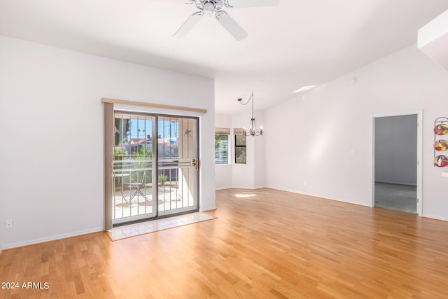 unfurnished room with vaulted ceiling, light hardwood / wood-style flooring, and ceiling fan with notable chandelier