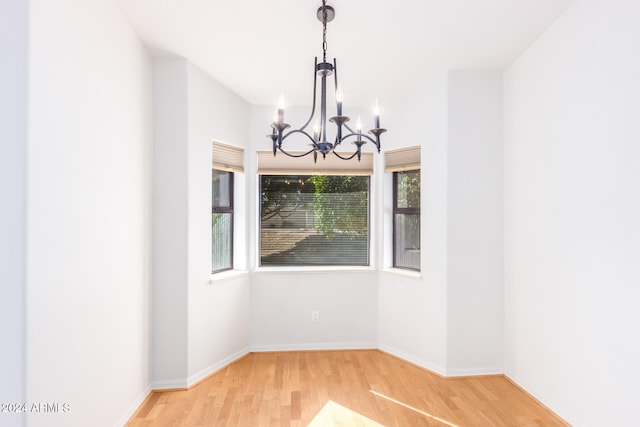 unfurnished dining area with hardwood / wood-style flooring and a chandelier