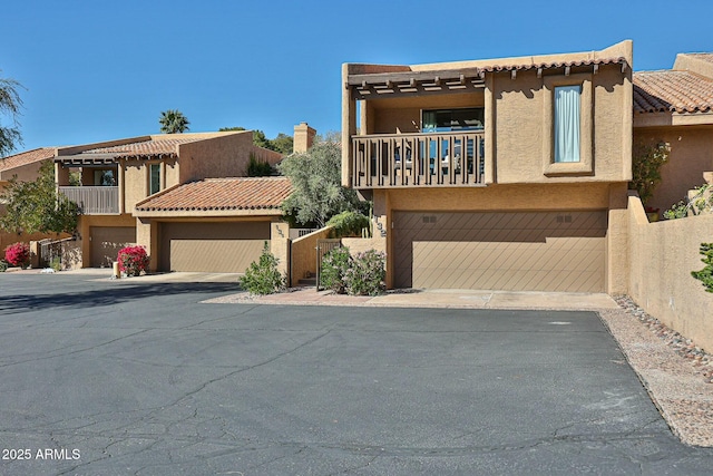 view of front of property featuring a garage, a tile roof, a balcony, and stucco siding