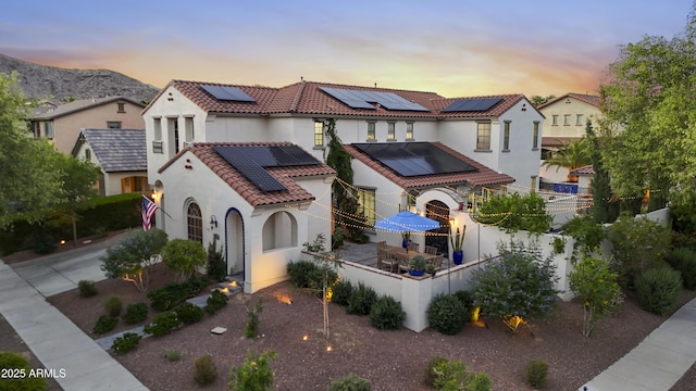 2985 N Point Ridge Rd, Buckeye, AZ 85396 - mediterranean / spanish-style home featuring roof mounted solar panels, stucco siding, a tiled roof, a fenced backyard, and a mountain view