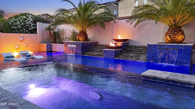 2985 N Point Ridge Rd, Buckeye, AZ 85396 - pool at dusk with an in-ground hot tub, an outdoor fire pit, and an outdoor pool