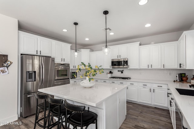 2985 N Point Ridge Rd, Buckeye, AZ 85396 - kitchen with appliances with stainless steel finishes, dark wood finished floors, white cabinets, backsplash, and a center island