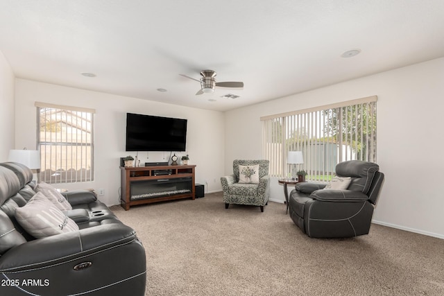 carpeted living room featuring a wealth of natural light, visible vents, baseboards, and ceiling fan