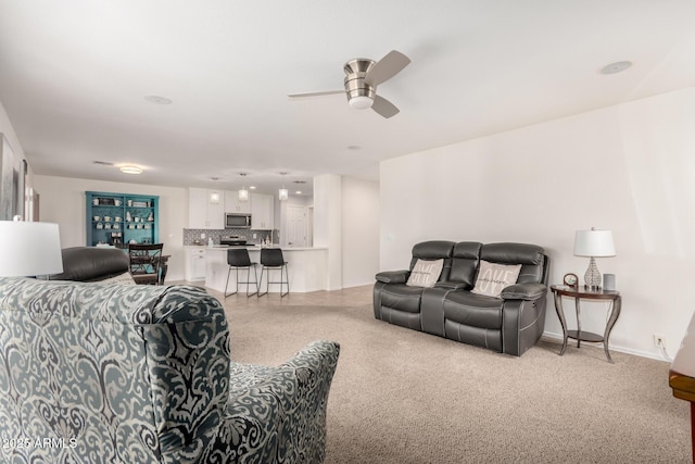 living area with baseboards and a ceiling fan