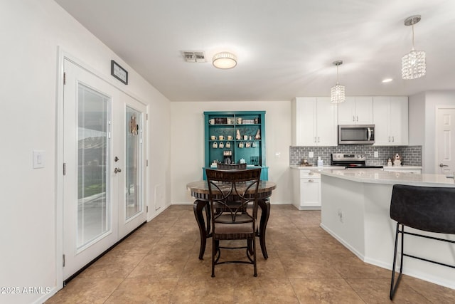 kitchen featuring visible vents, stainless steel appliances, white cabinets, light countertops, and decorative backsplash