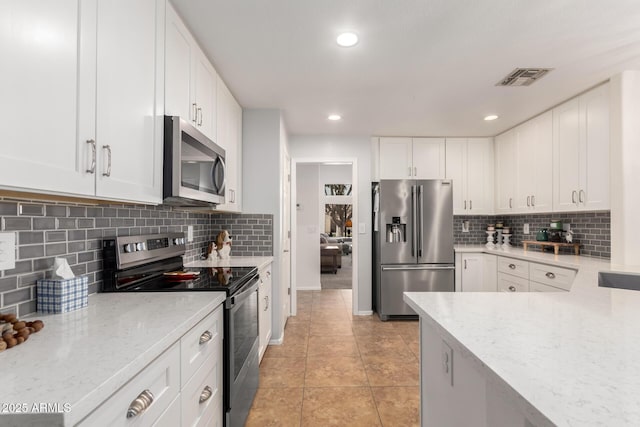 kitchen with visible vents, light stone counters, decorative backsplash, appliances with stainless steel finishes, and white cabinets