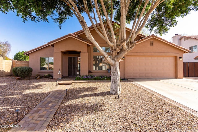 view of front of home with an attached garage, fence, driveway, and stucco siding