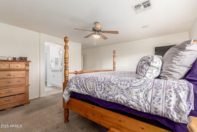 carpeted bedroom with ceiling fan, visible vents, and ensuite bath