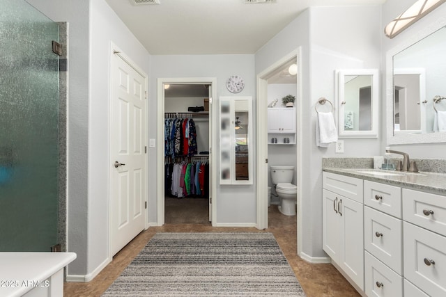 bathroom with a spacious closet, visible vents, toilet, a shower with shower door, and vanity