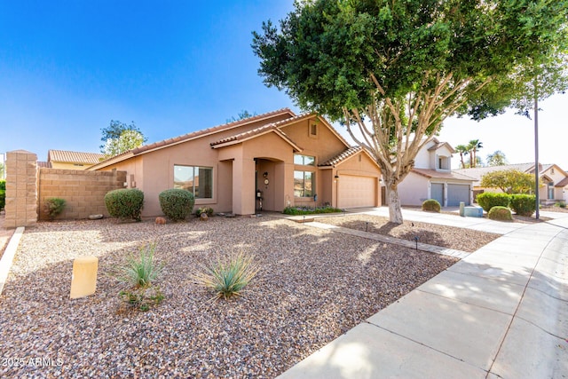 view of front of home with stucco siding, a tile roof, fence, concrete driveway, and an attached garage