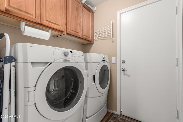 clothes washing area featuring baseboards, cabinet space, and washing machine and dryer