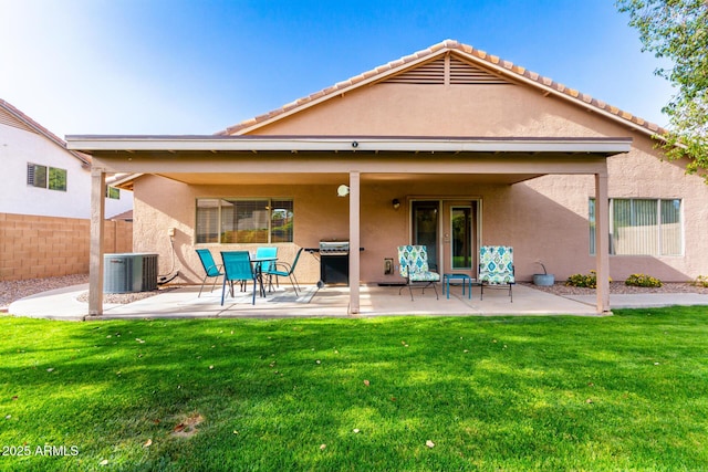 back of house with stucco siding, a lawn, and a patio area