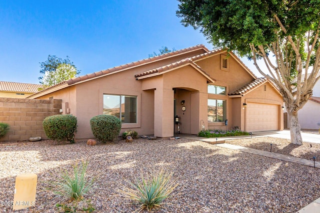 view of front of home with stucco siding, an attached garage, concrete driveway, and fence