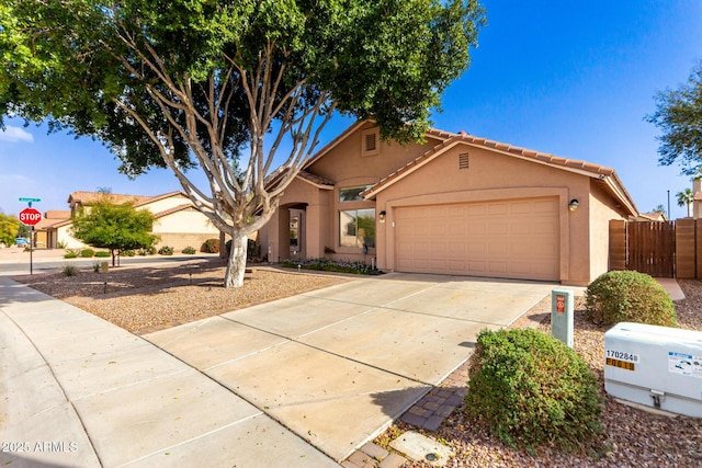 view of front of home with fence, an attached garage, stucco siding, concrete driveway, and a tile roof