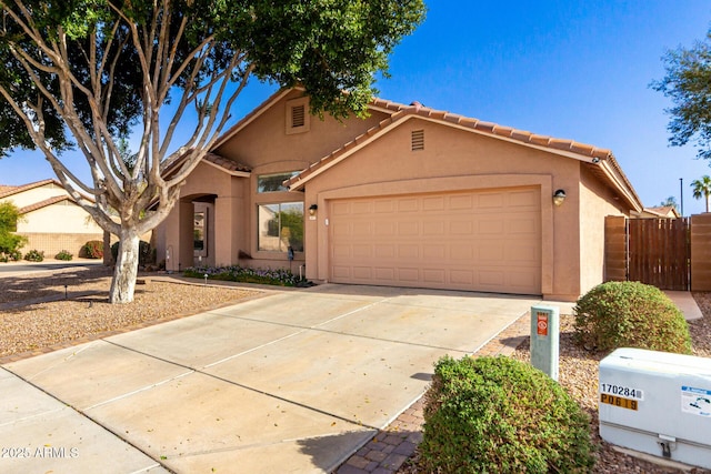 view of front of property with fence, a tiled roof, concrete driveway, stucco siding, and an attached garage