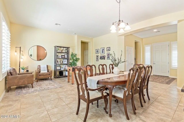 dining space with a wealth of natural light, light tile patterned floors, and an inviting chandelier