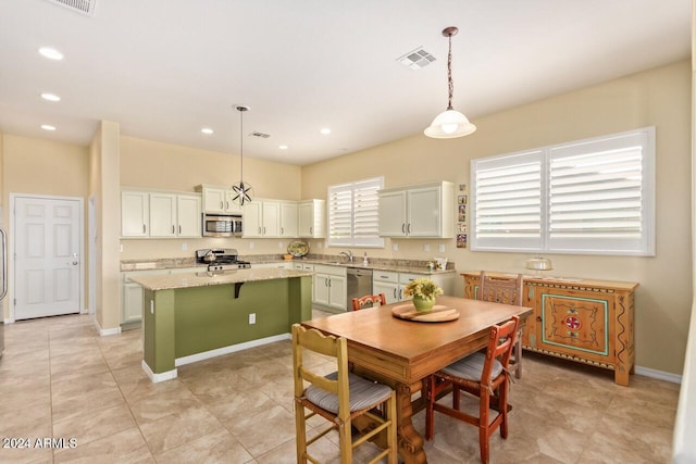 kitchen with light stone counters, stainless steel appliances, a kitchen island, a kitchen bar, and hanging light fixtures