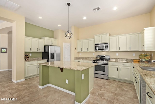 kitchen with stainless steel appliances, light tile patterned flooring, light stone counters, a center island, and pendant lighting