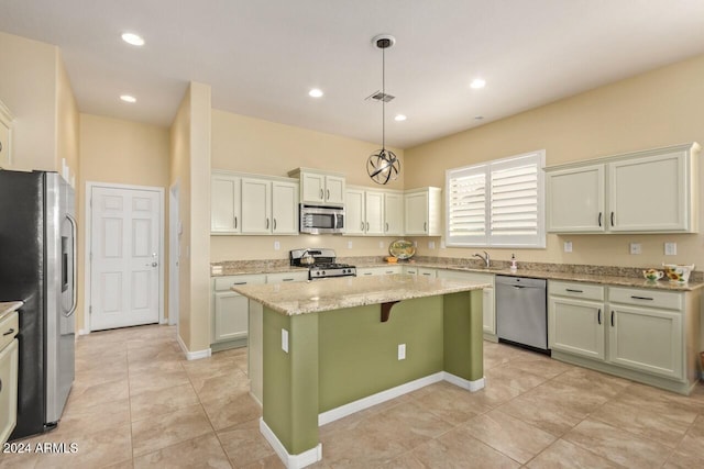 kitchen featuring light stone counters, appliances with stainless steel finishes, light tile patterned floors, a center island, and pendant lighting