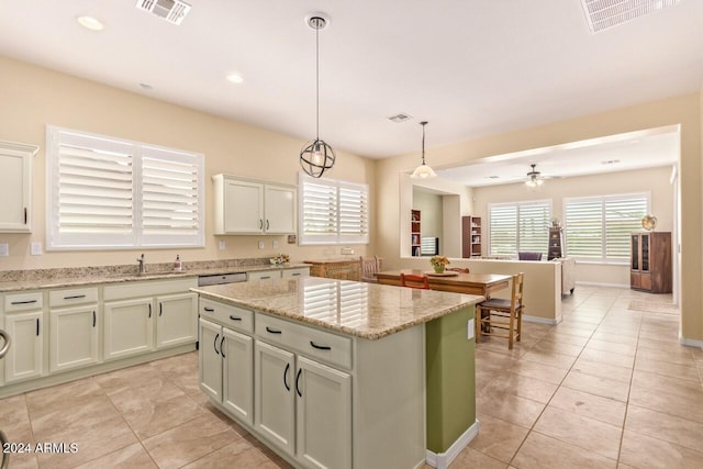 kitchen featuring light stone countertops, ceiling fan, light tile patterned floors, hanging light fixtures, and a kitchen island