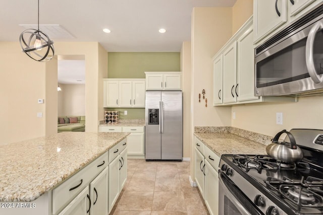 kitchen featuring stainless steel appliances, light stone counters, pendant lighting, light tile patterned floors, and white cabinetry