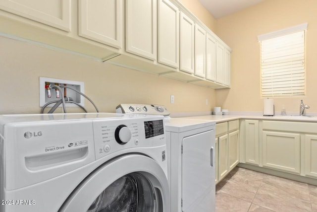 clothes washing area with washing machine and dryer, cabinets, sink, and light tile patterned floors