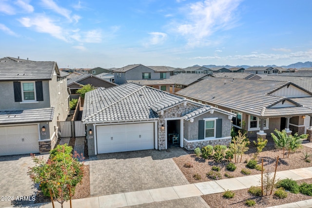 view of front of property featuring stone siding, a residential view, decorative driveway, and a tiled roof