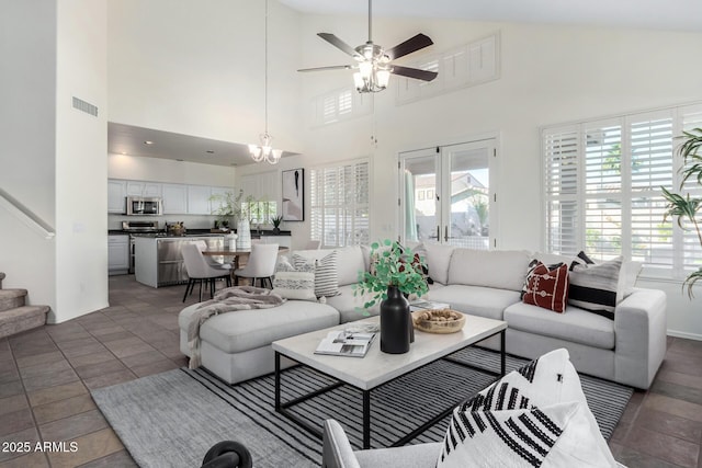 living room featuring ceiling fan with notable chandelier, tile patterned floors, and a towering ceiling