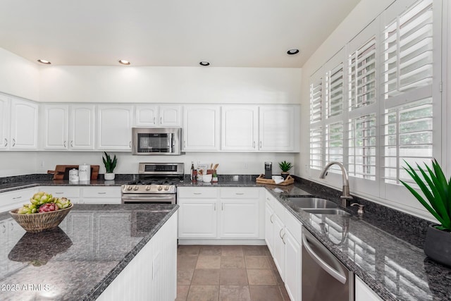 kitchen with sink, dark stone countertops, white cabinetry, and appliances with stainless steel finishes